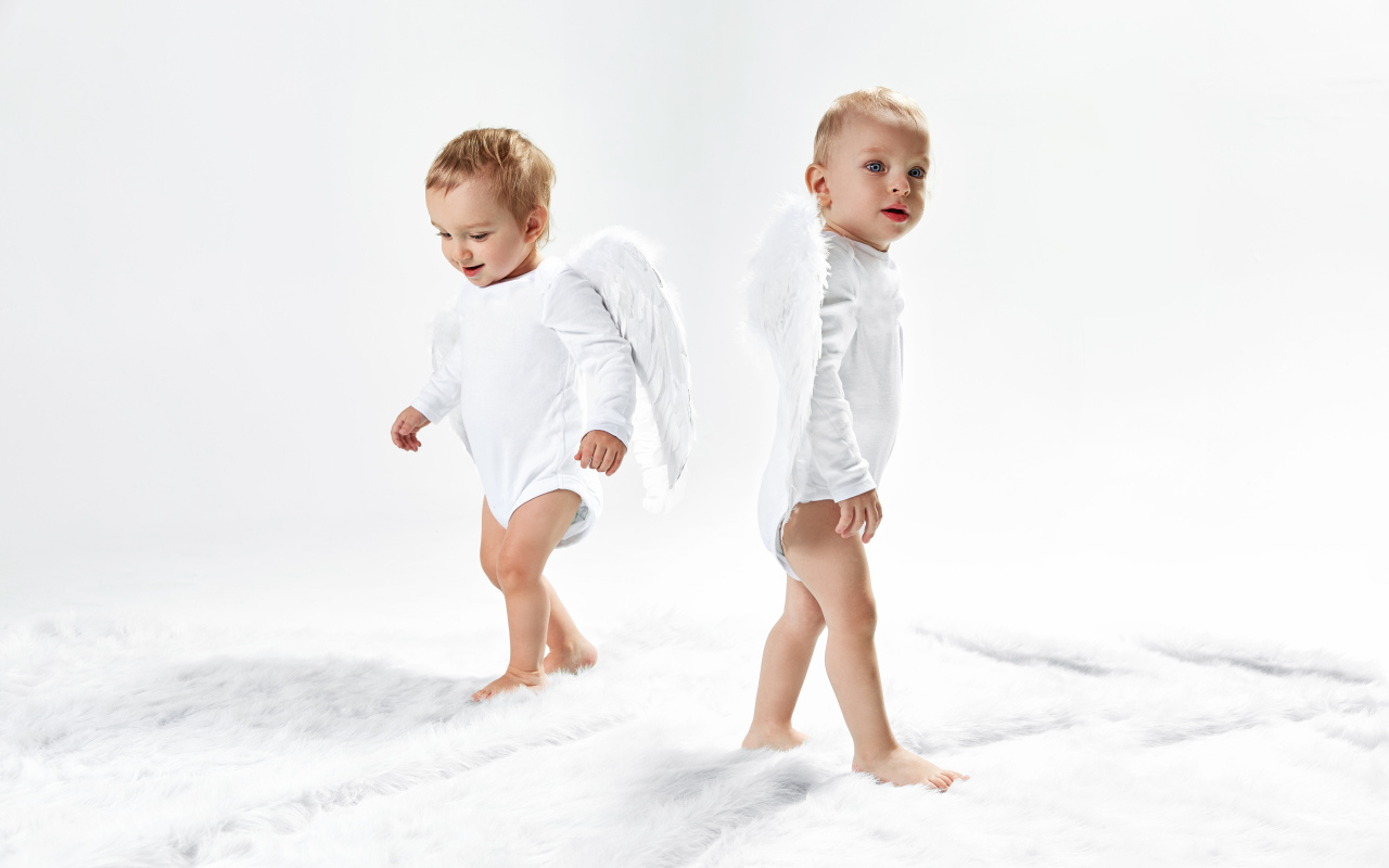 Два маленьких мальчика в костюмах ангела на белом фоне