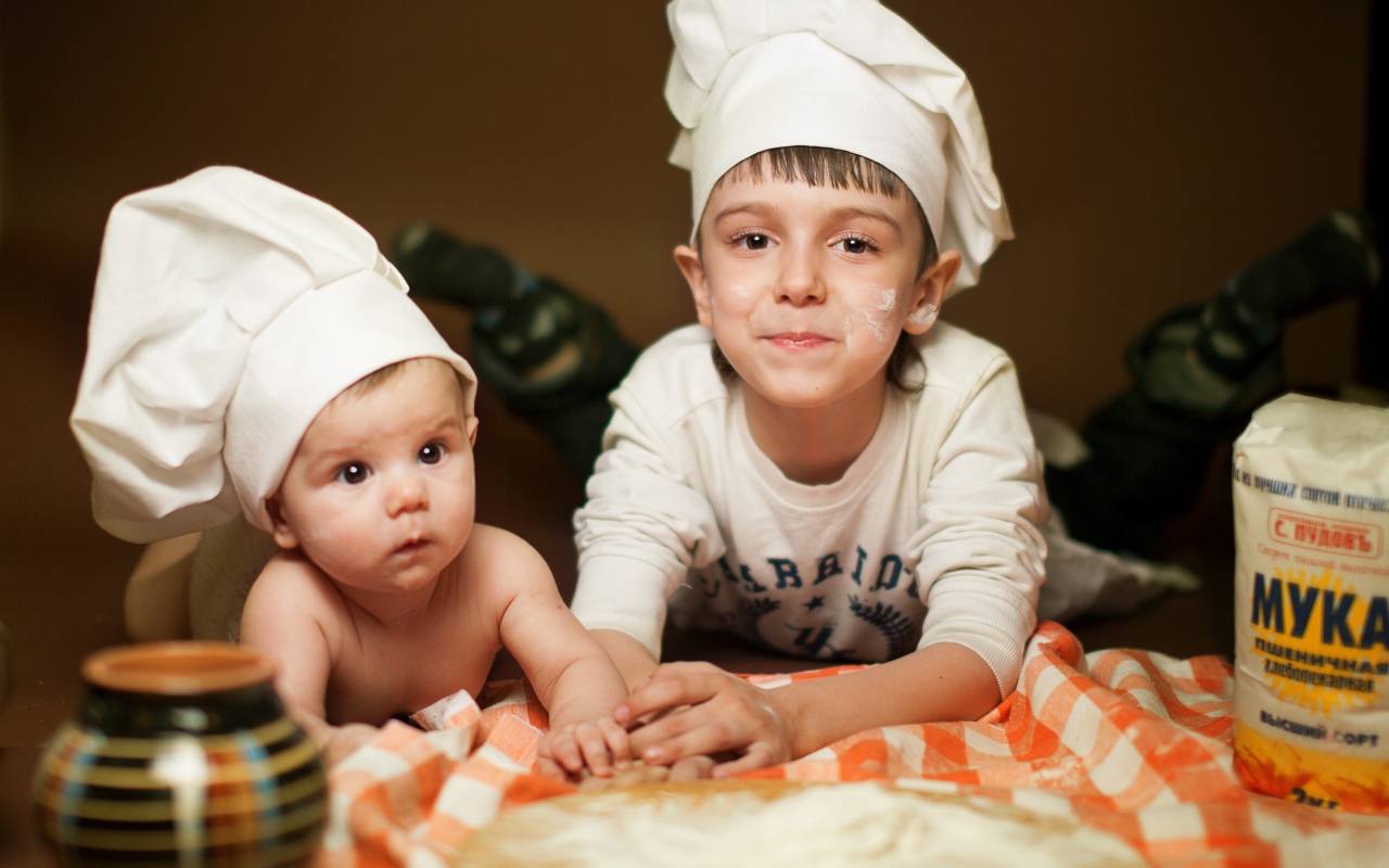 Два маленьких мальчика в шапках повара на кухне