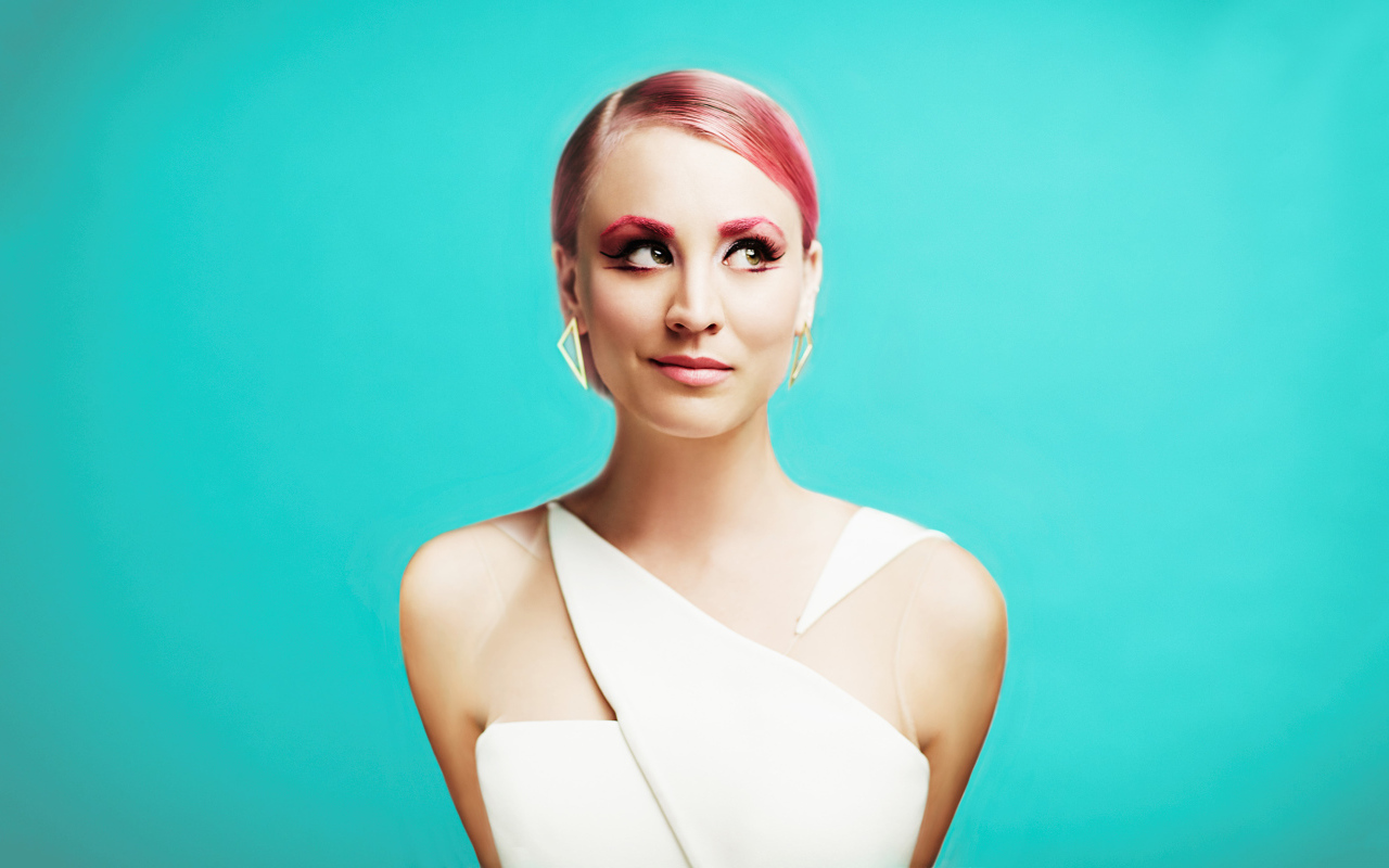 Актриса Кейли Куоко с ярким макияжем на голубом фоне
