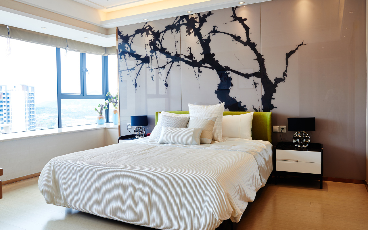 Красивая светлая спальня с большой кроватью и рисунком на стене 