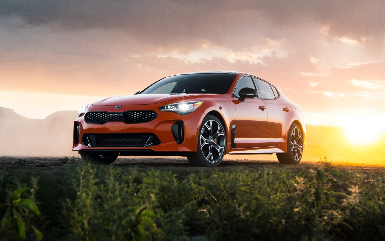 Оранжевый автомобиль  Kia Stinger GTS, 2020 года на закате