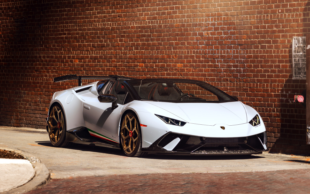 Белый быстрый Lamborghini Huracan стоит у кирпичной стены