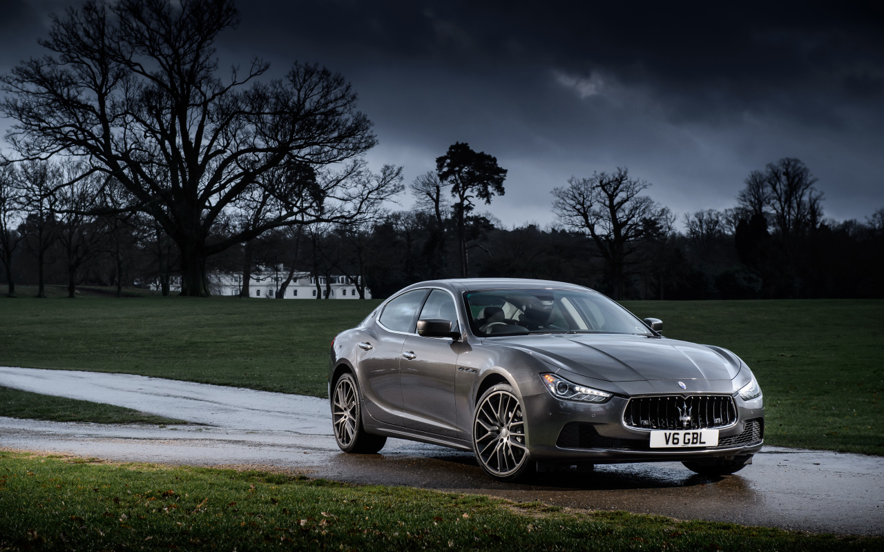 Серебристый автомобиль Maserati Ghibli на фоне грозового неба