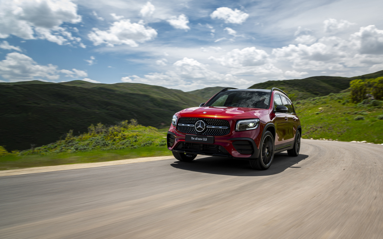 Красный автомобиль Mercedes-Benz GLB-Class  на фоне зеленых холмов