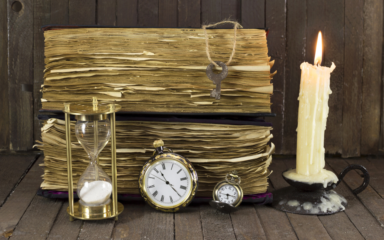 Старинные книги, зажженная свеча, ключи и часы на столе