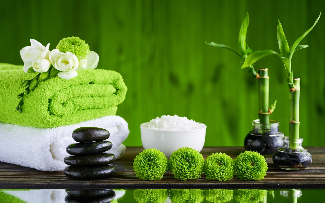 Черные камни, полотенца, соль и цветы у воды для SPA