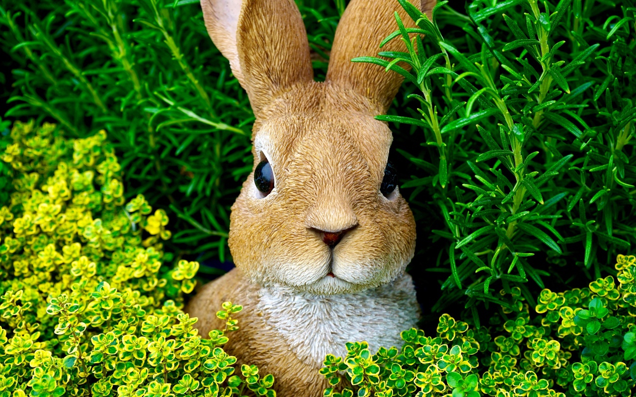 Статуэтка кролика в зеленой траве 