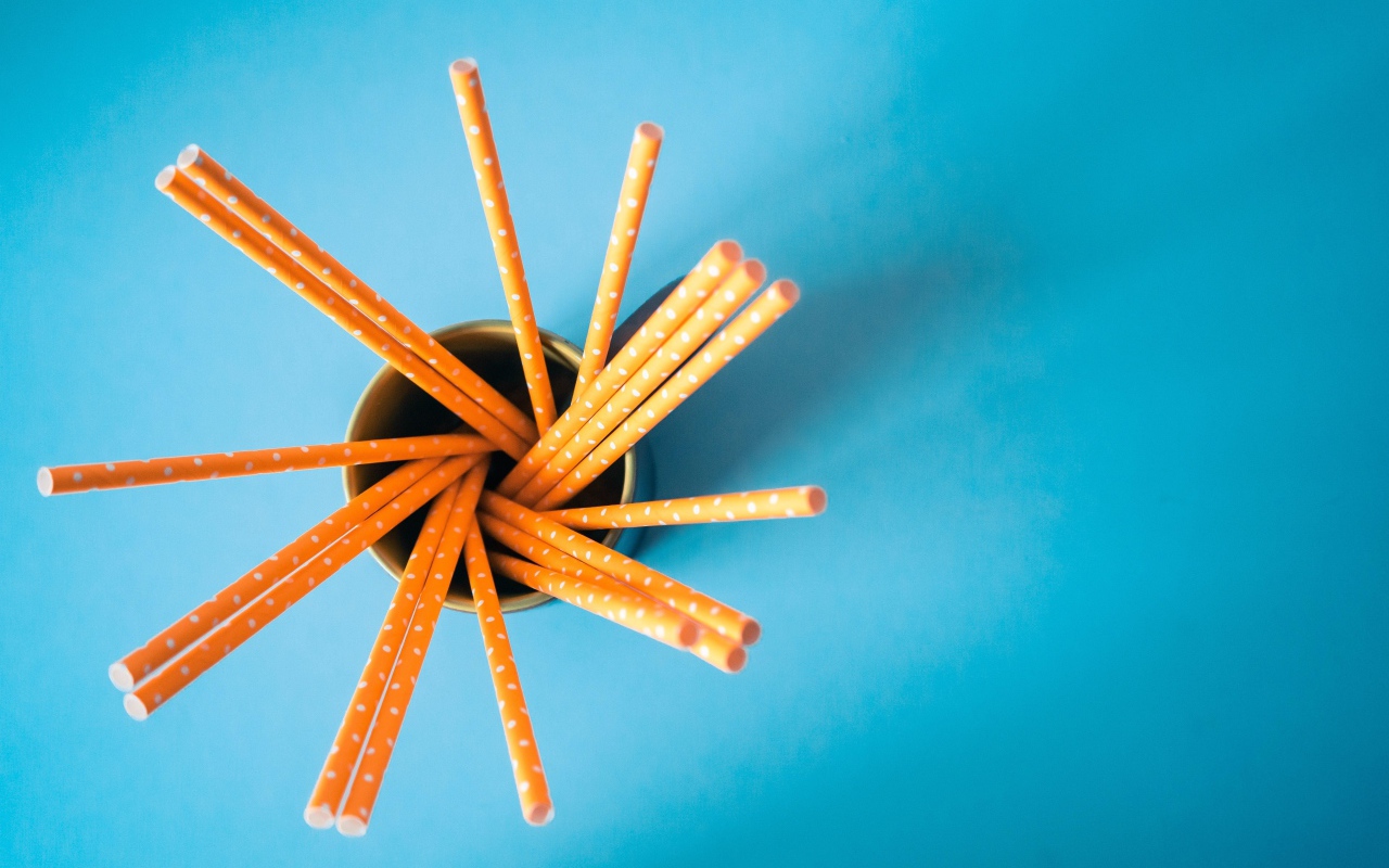 Трубочки в стакане на голубом столе