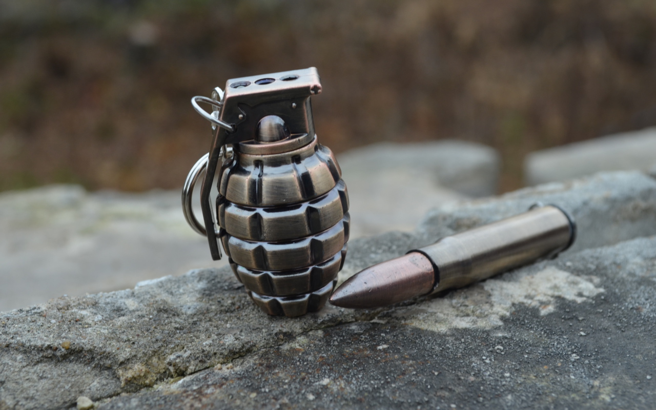 Боевая граната с патроном лежат на камне 