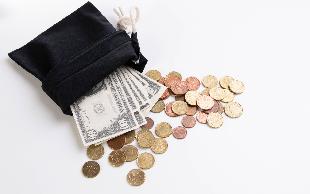 Кошелек с монетами и долларами на белом фоне