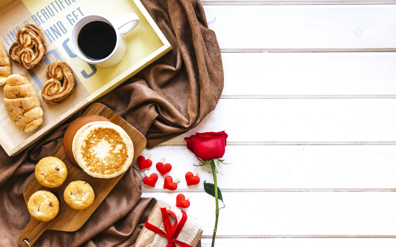 Выпечка на столе с кофе, подарком и красной розой