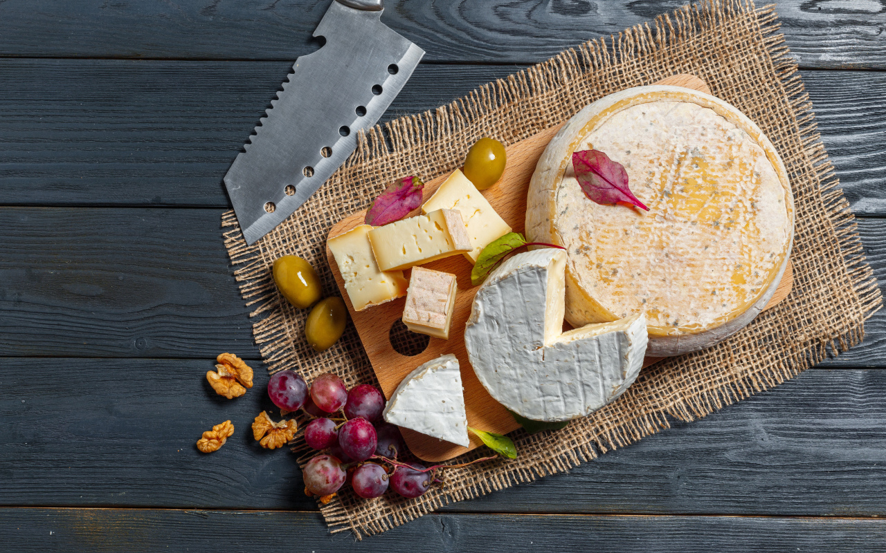 Сыр с плесенью на столе с орехами и виноградом 