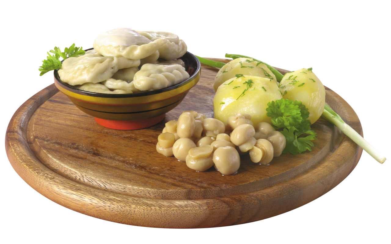 Вареники с грибами и вареной картошкой на деревянной доске на белом фоне