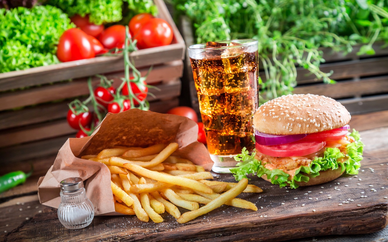 Картофель фри, гамбургер, кола и помидоры на столе