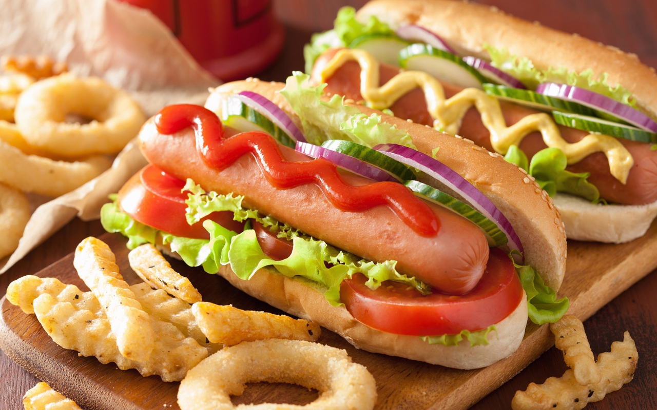 Хотдоги с овощами на разделочной доске с картофелем фри