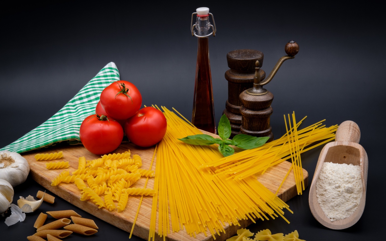 Макаронные изделия на столе с мукой, помидорами и специями