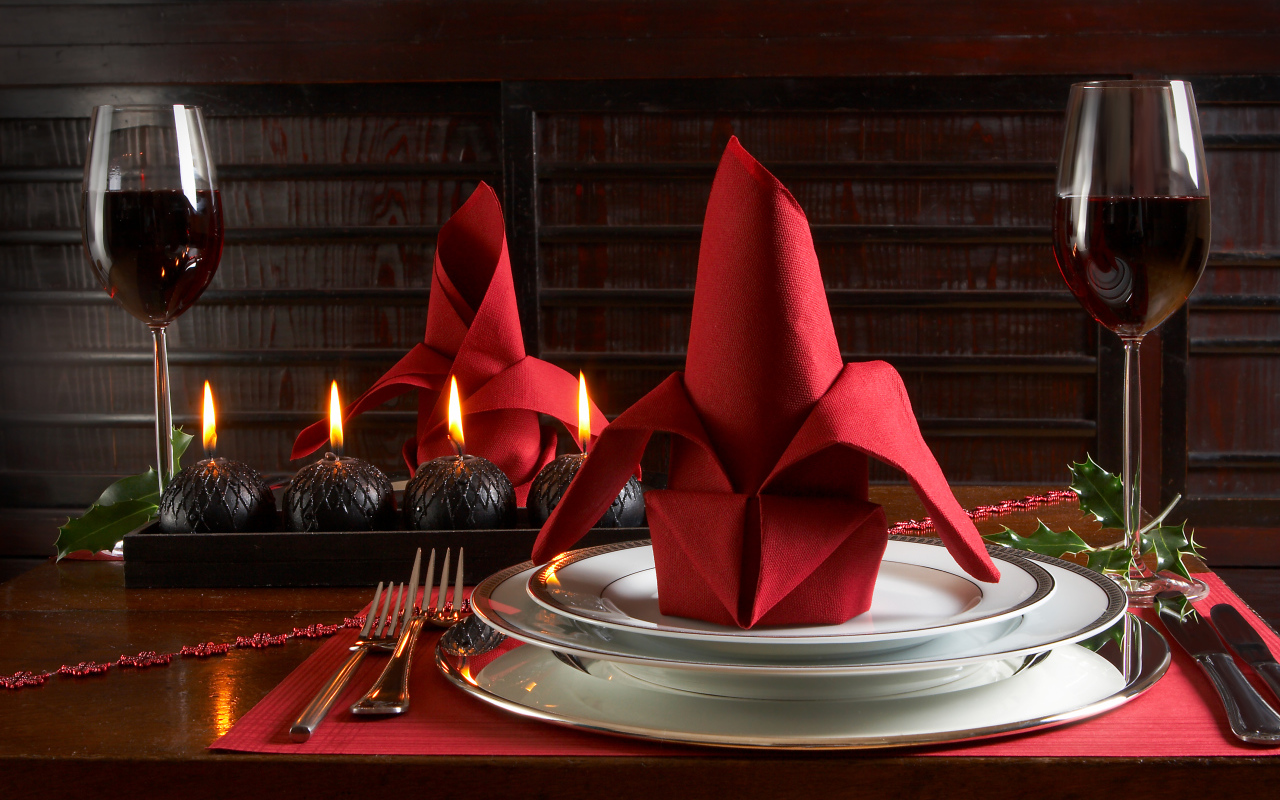 Красная салфетка на тарелке на столе с бокалами вина и свечами