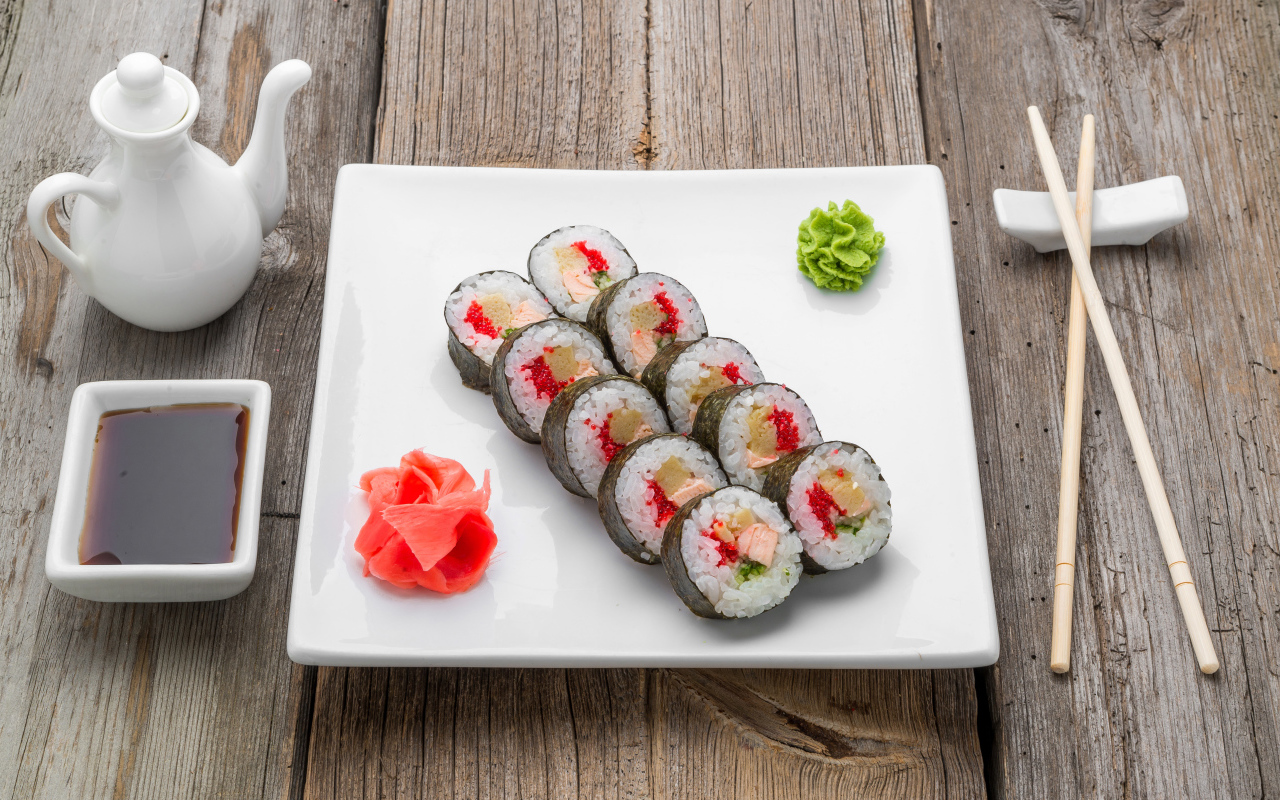 Суши на большой белой тарелке с соусом васаби и имбирем на столе соевым соусом