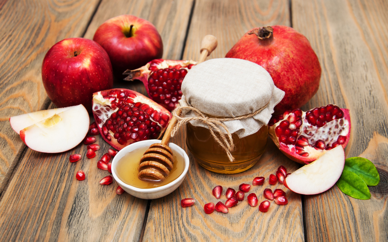 Банка меда на столе с гранатами и яблоками
