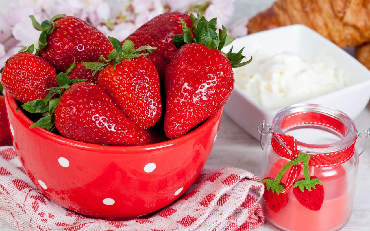 Свежие ягоды клубники в красной миске на столе