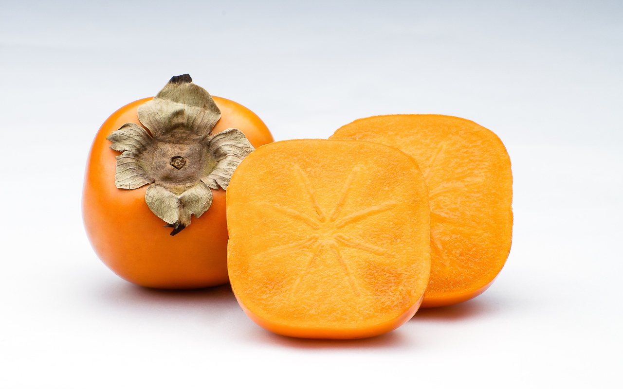 Оранжевая хурма на сером фоне крупным планом