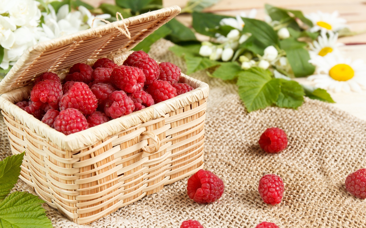 Плетеная корзина на столе с ягодами малины 