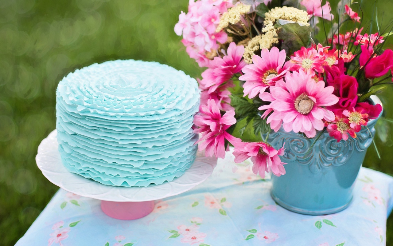 Красивый торт с голубой глазурью на столе с букетом