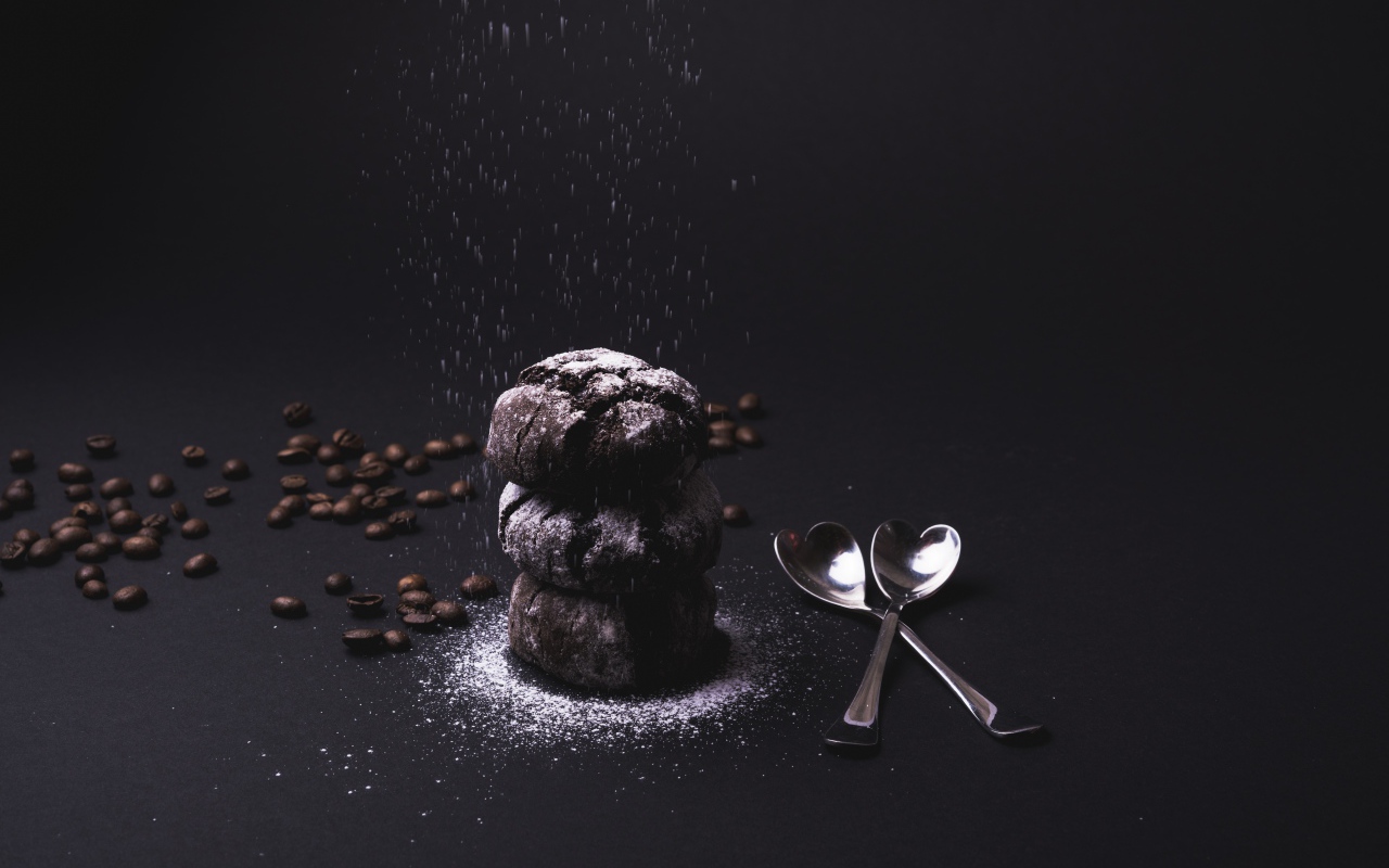 Шоколадное печенье с сахарной пудрой на черном фоне с кофейными зернами