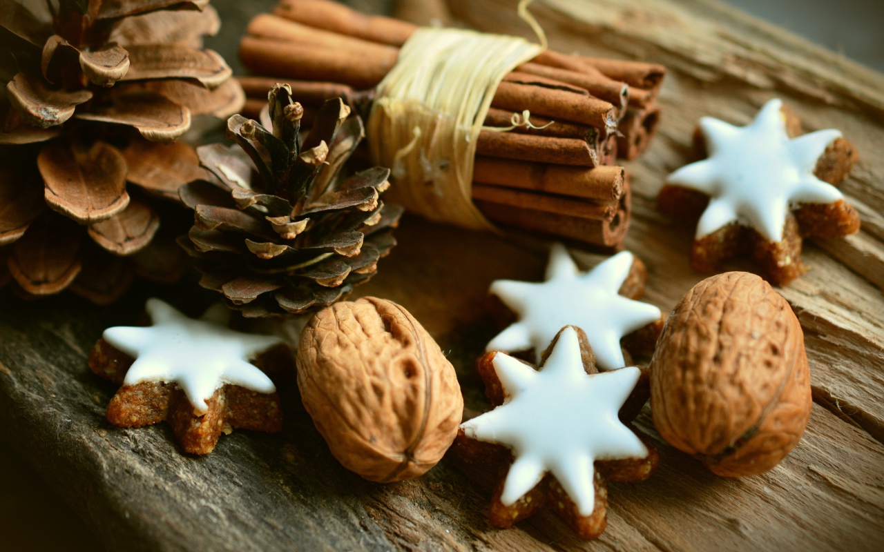 Печенье, орехи, палочки корицы и еловые шишки на деревянном столе