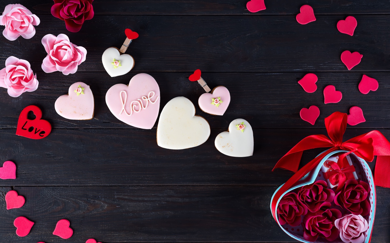 Печенье с глазурью на черной поверхности с сердечками и подарком