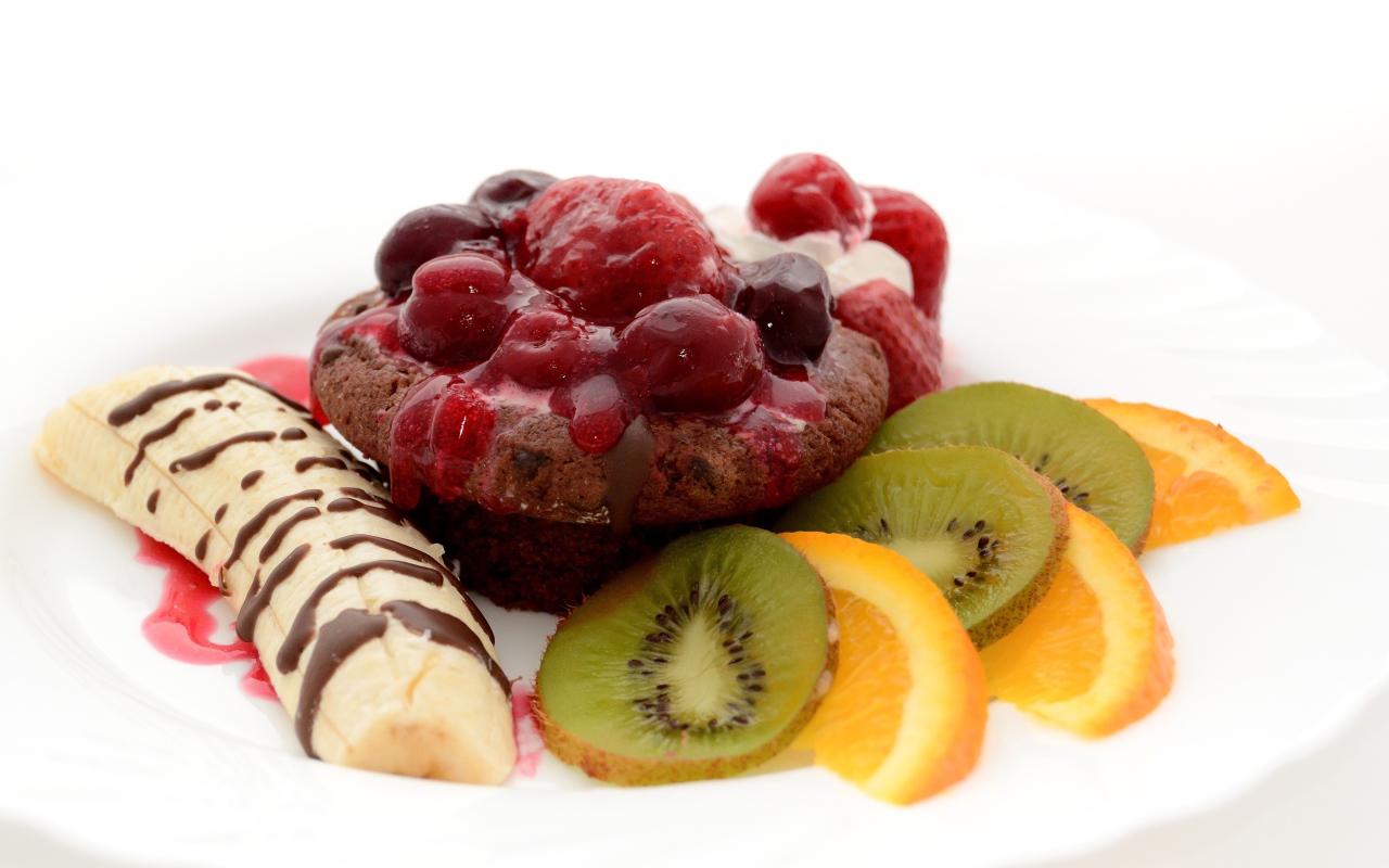 Печенье с вареньем, кусочками банана, киви и апельсина на белом фоне