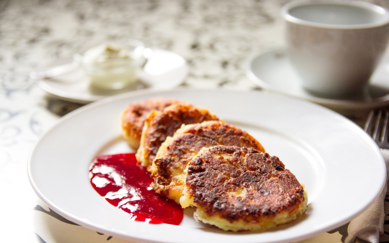 Аппетитные сладкие сырники с джемом на белой тарелке