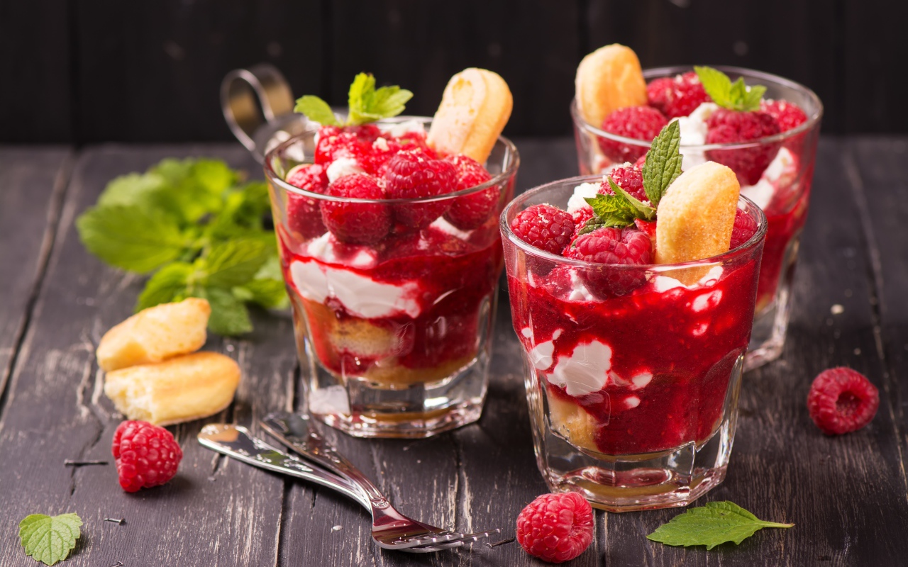 Десерт с печеньем и малиной на столе с вилками