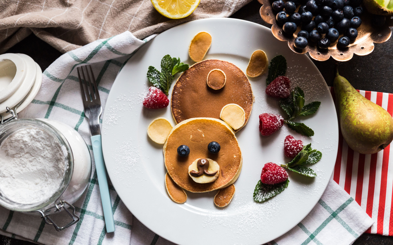 Медведь из оладьев на тарелке с малиной и сахарной пудрой