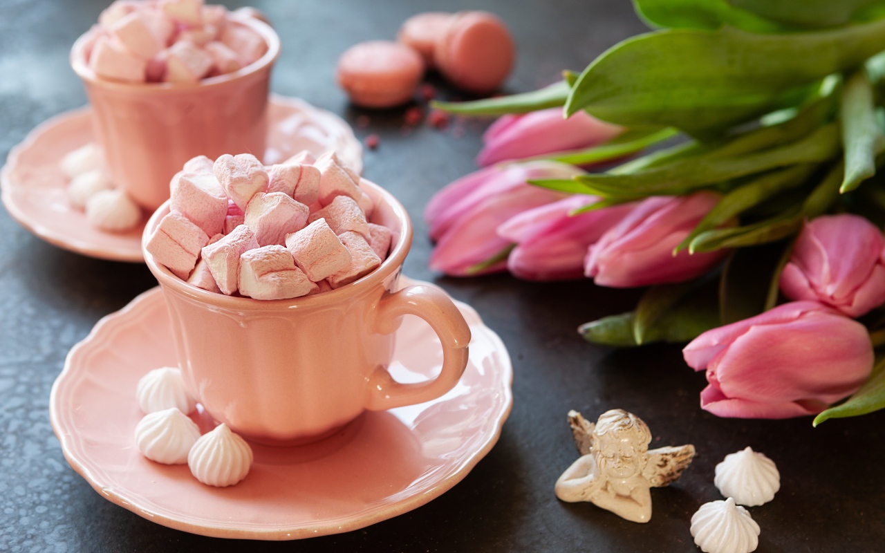 Маршмеллоу в розовой чашке на столе с букетом тюльпанов