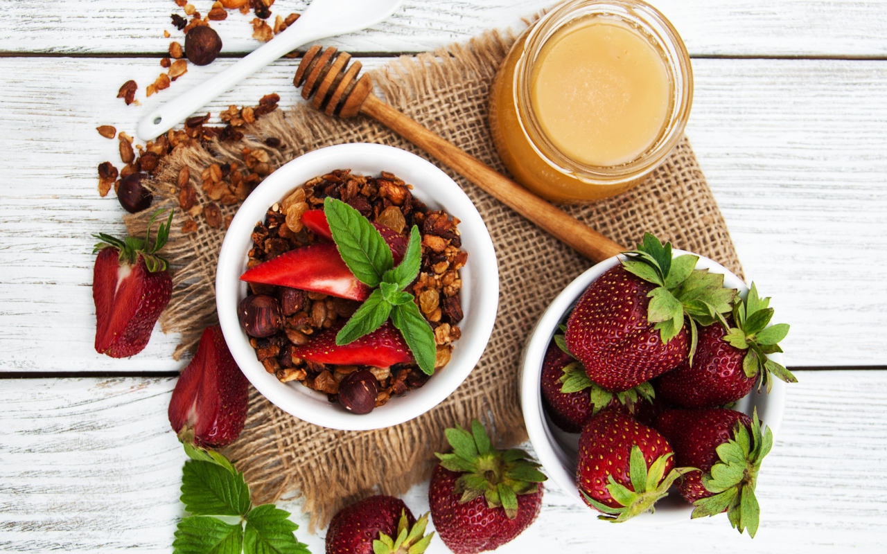 Орехи с ягодами клубники и медом на столе