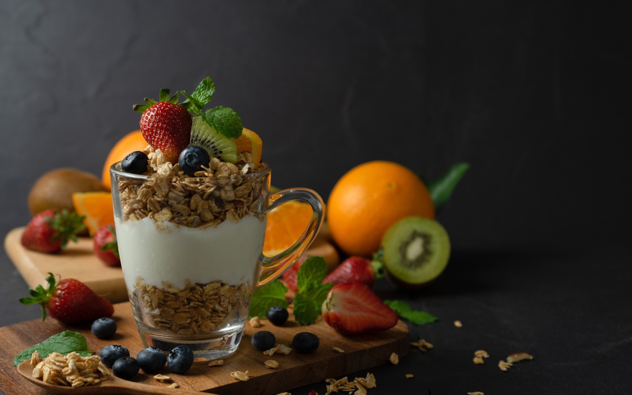 Овсяные хлопья с чашке с йогуртом на столе с ягодами и фруктами