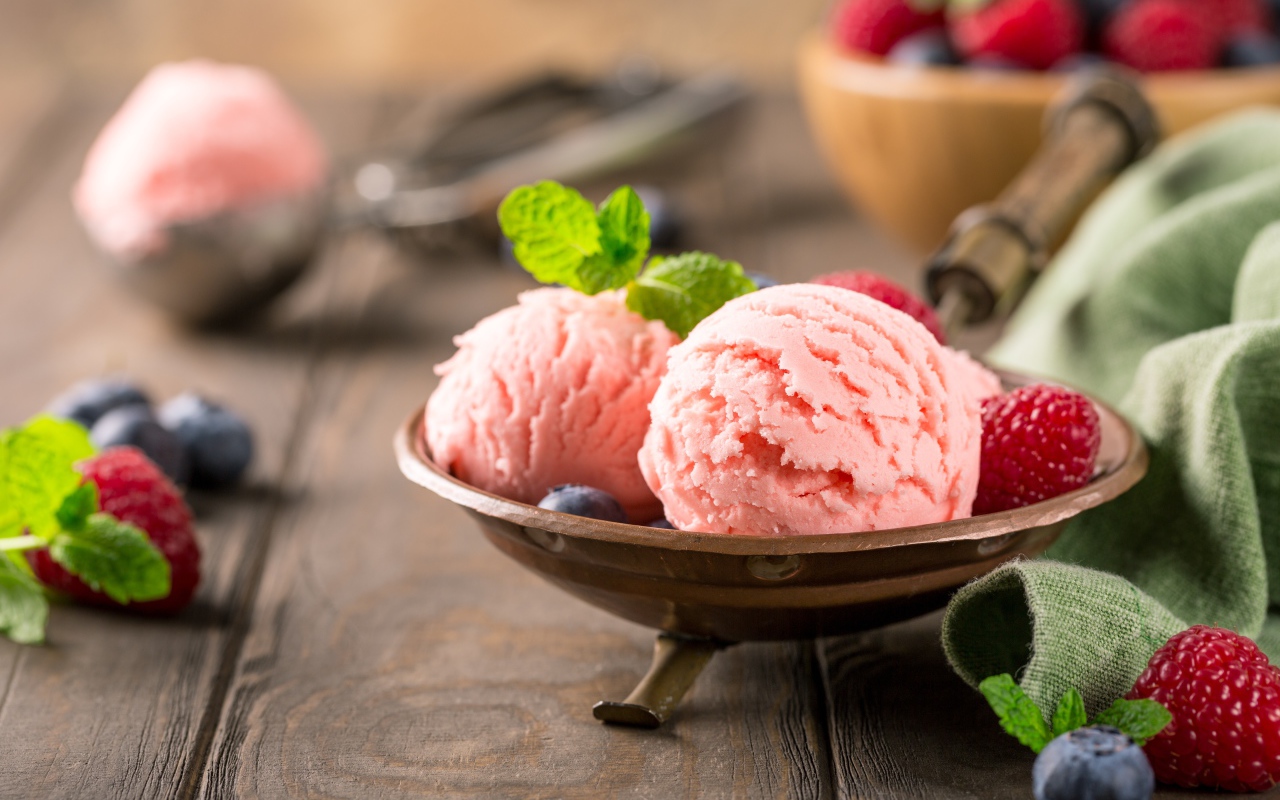 Шарики фруктового мороженого на столе с ягодами малины и черники 