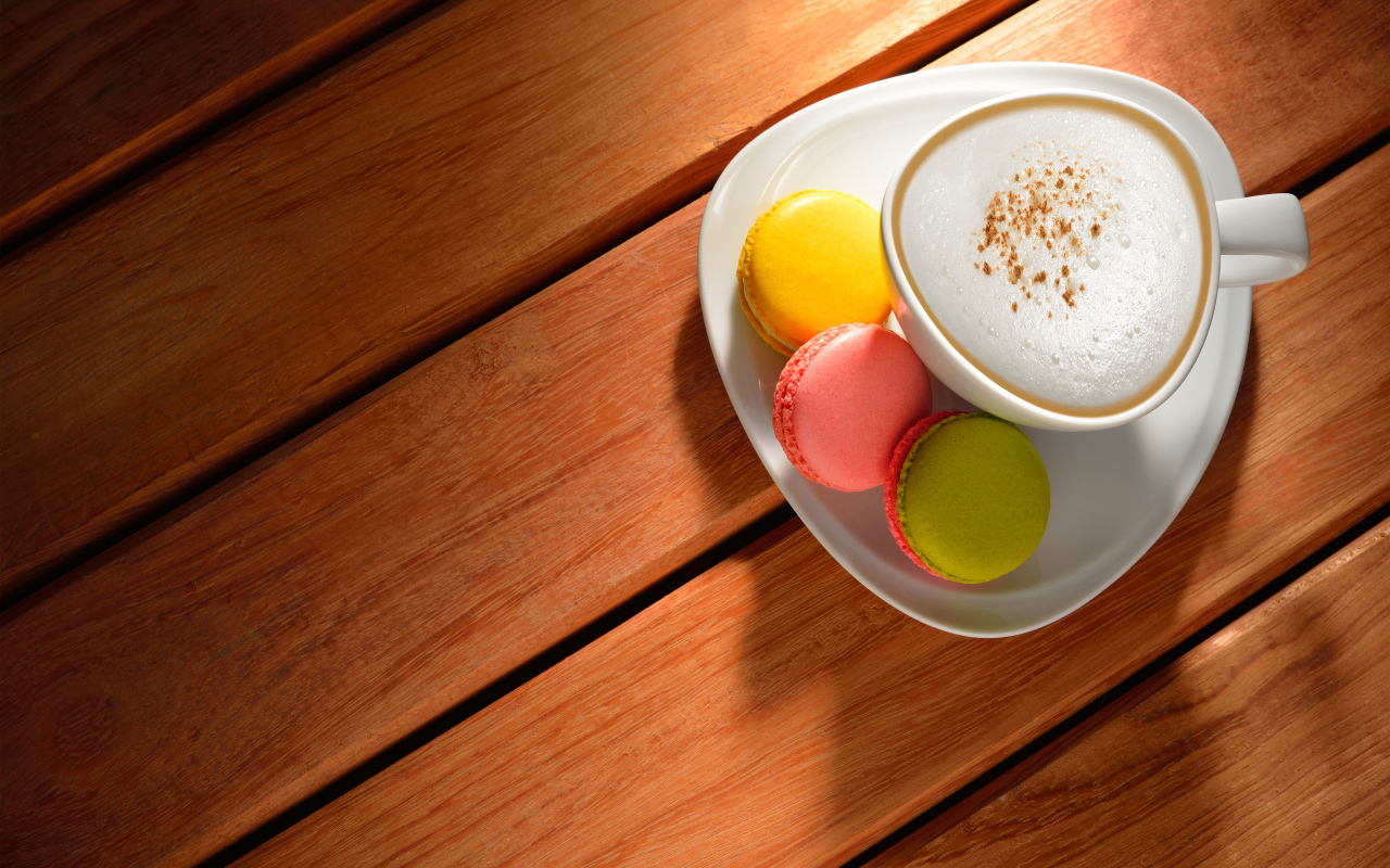 Чашка капучино на блюдце с печеньем макарон