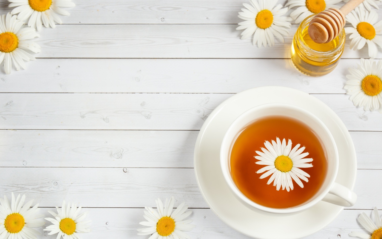 Чашка чая с ромашкой на столе с медом