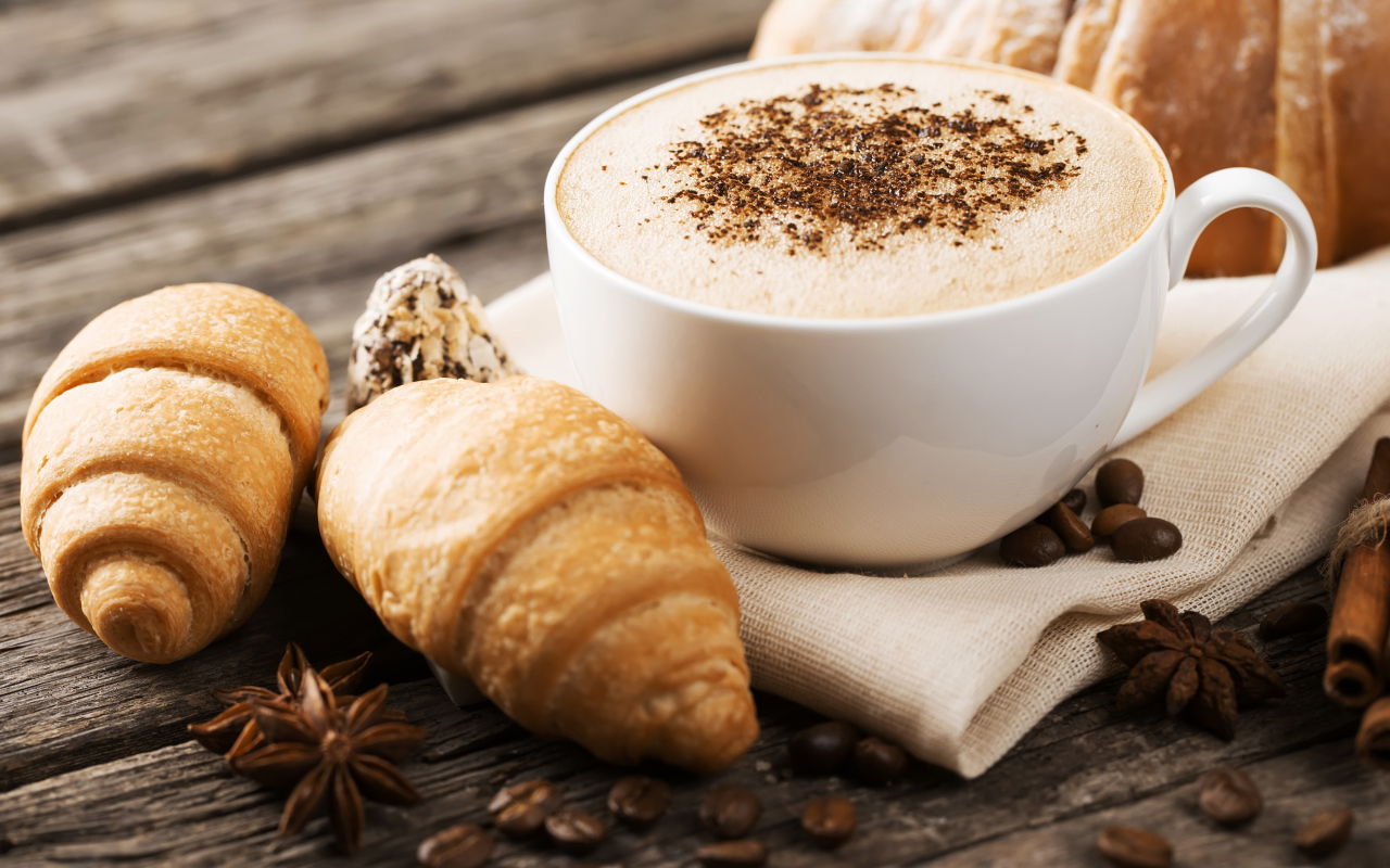 Чашка капучино на столе круассанами