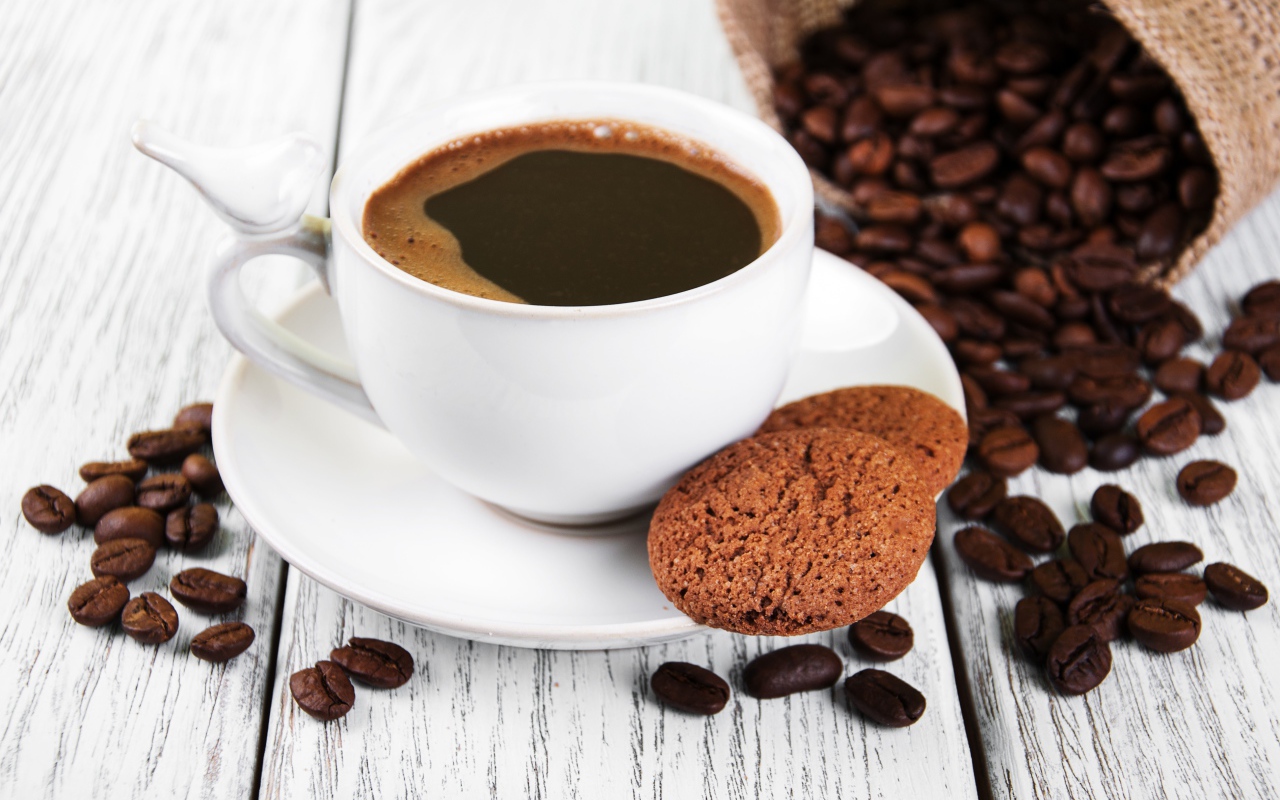 Чашка кофе на столе с кофейными зернами и печеньем
