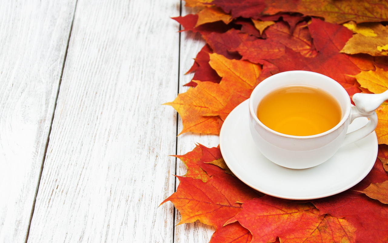 Чашка чая на столе с осенней листвой 
