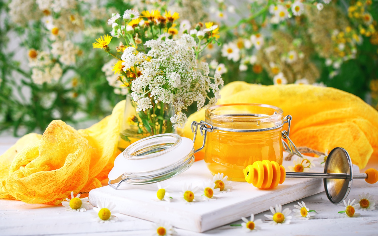 Банка меда на столе с цветами