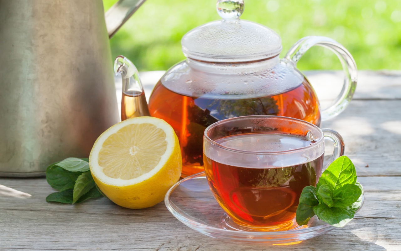 Чайник с чаем на столе с чашкой и половиной лимона