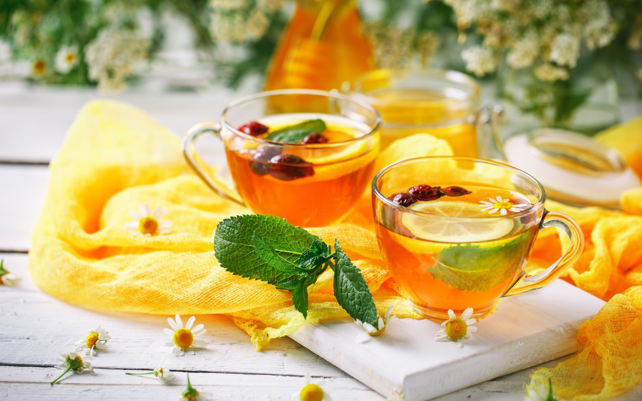 Две стеклянные чашки чая с лимоном, мятой и шиповником