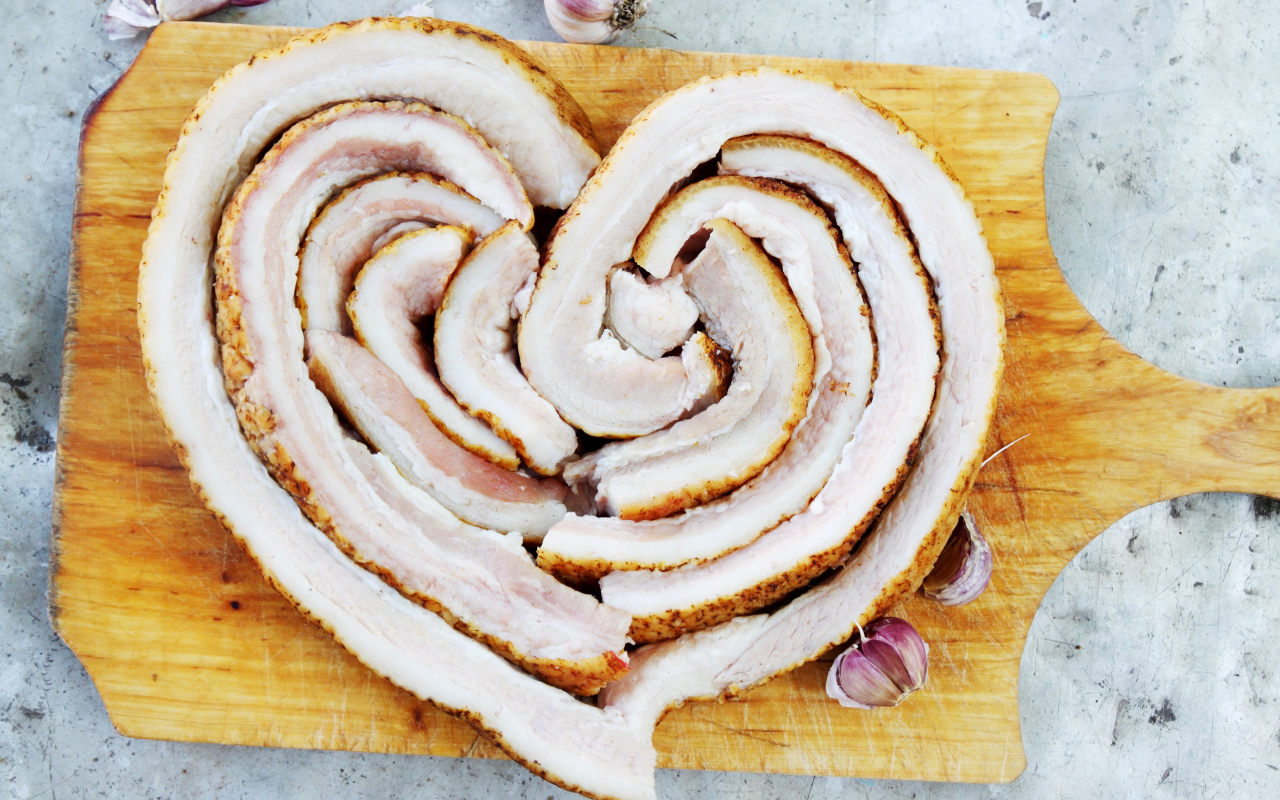 Сердце из свежего сала на доске с чесноком