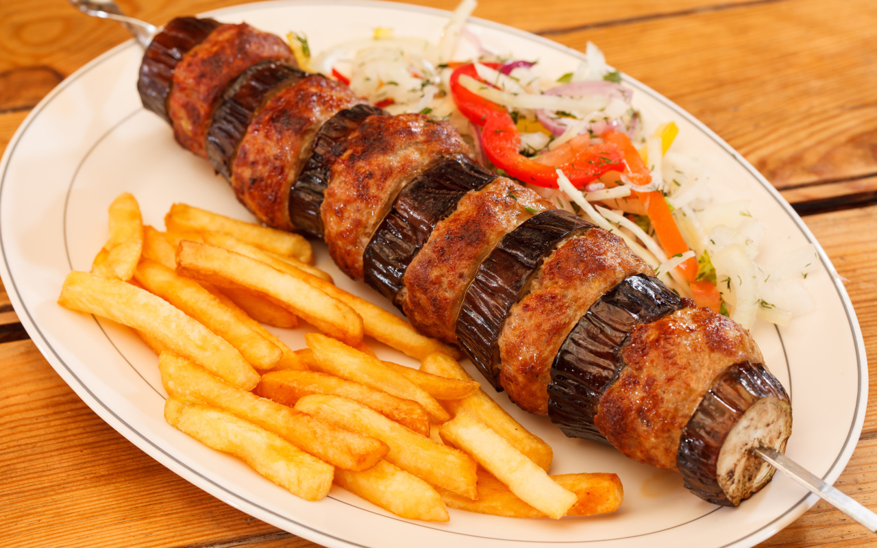 Шашлык с мясом и баклажанами на тарелке с картофелем фри 