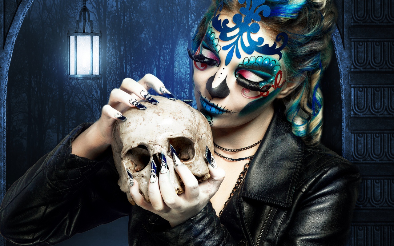 Девушка с гримом на лице с черепом в руках на Хэллоуин 