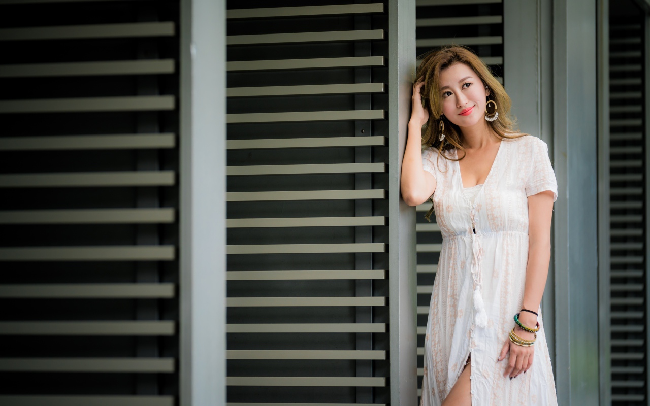 Красивая девушка азиатка в платье стоит у дверей